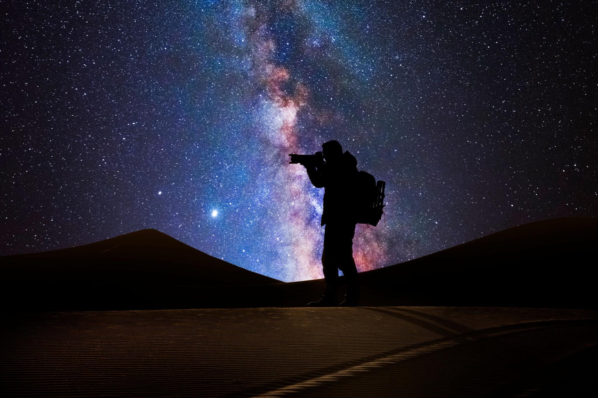 A lone figure silhouetted beneath the Milky Way